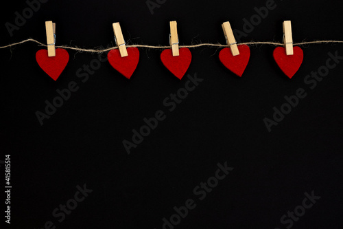 Red heart hanging on the clothesline  on black background. Valentines Day