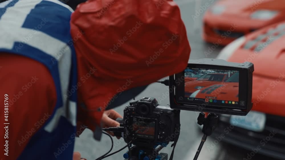Close-up of camera man wearing protective vest filming sports car at motor show