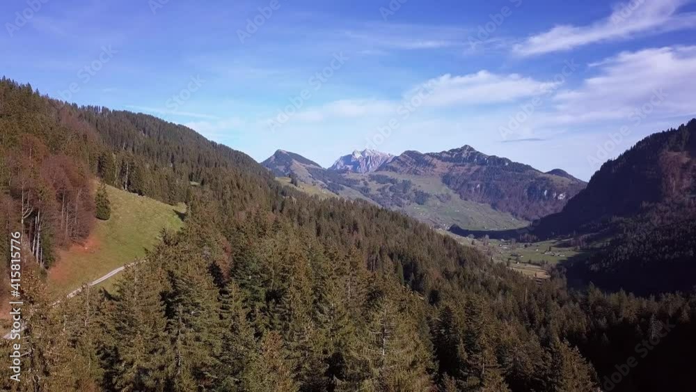 A tiny dirt road winds through sun drenched fall valley near Toggenburg, Switzerland, aerial descend A tiny dirt road winds through sun drenched fall valley near Toggenburg, Switzerland, aerial descend