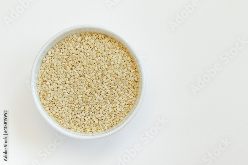 Sesame seeds in a glass bowl, isolated on white background. Top view.