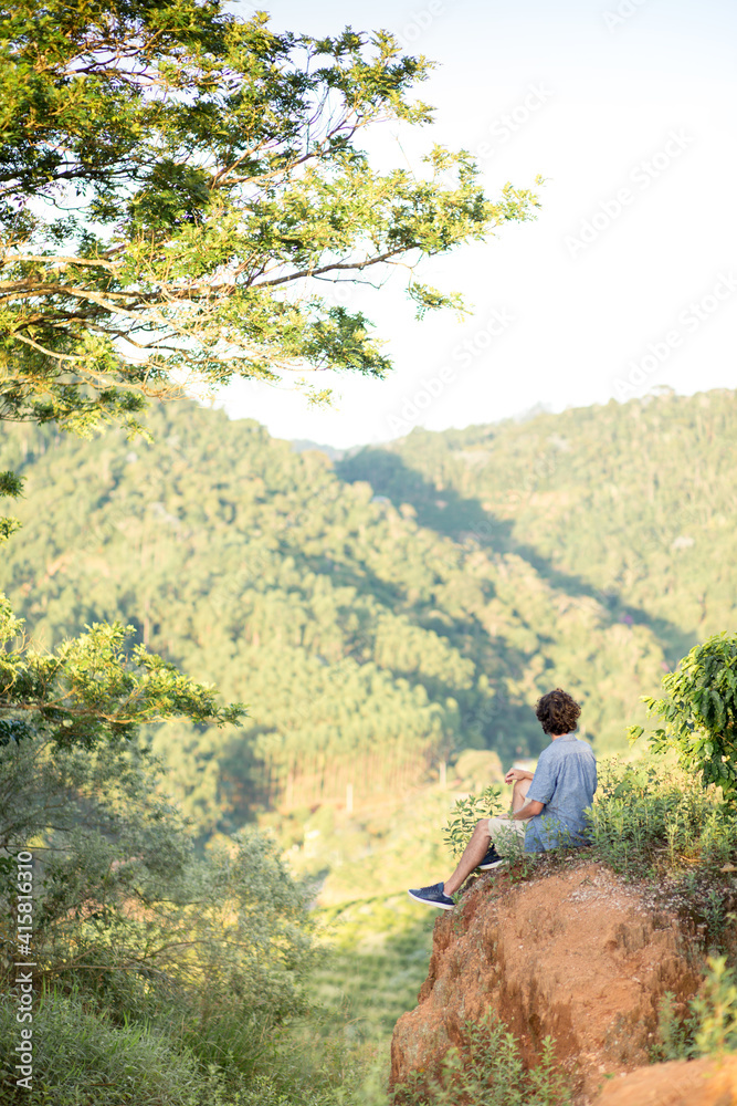 Adventurous young man sitting on the top of a mountain. Adventure travel.