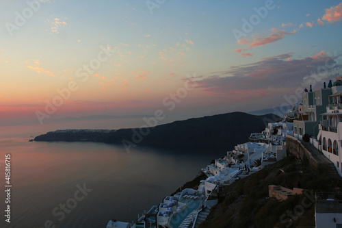 Beautiful pink sunset on the ocean coast of the southern city. Santorini coastal landscape.