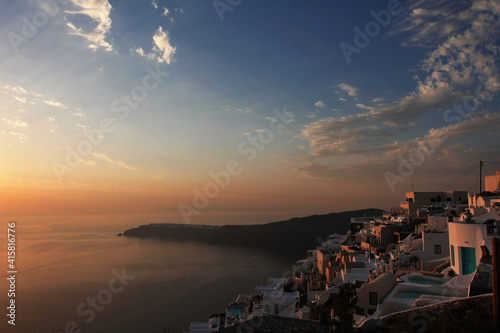 Beautiful orange sunset on the ocean coast of the southern city. Santorini coastal landscape.