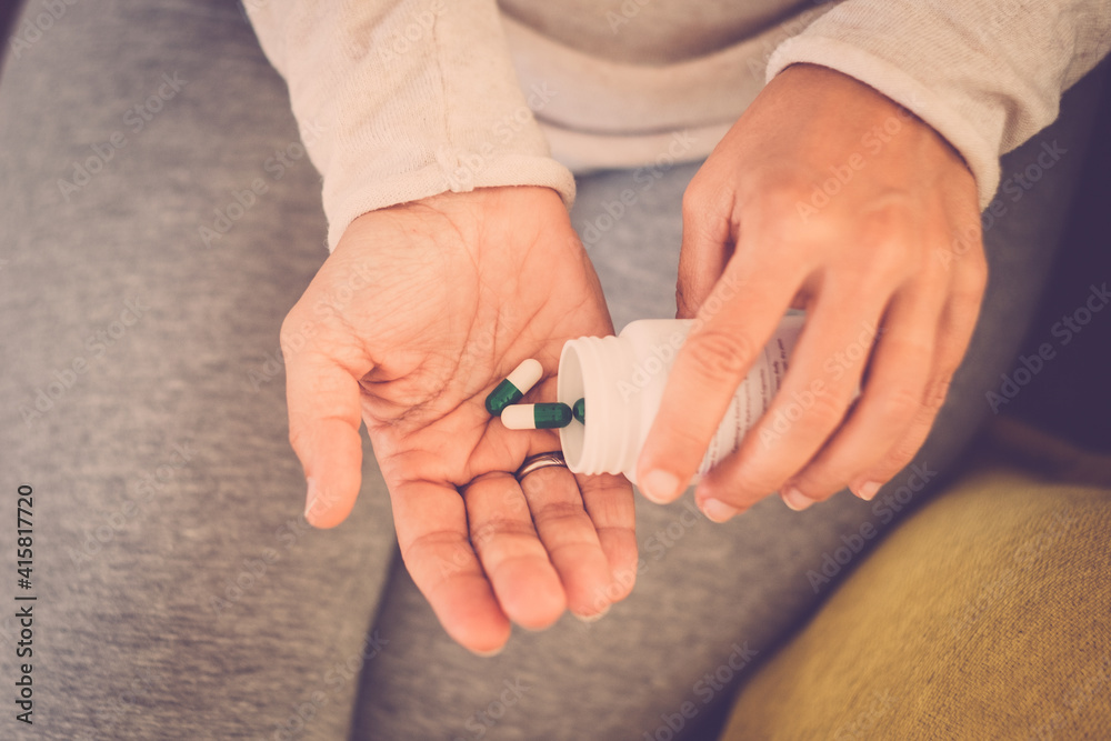 Close up of couple of two hands of woman taking pills and medicaments alone and isolated at home on the sofa. Close up of couple of two hands of woman taking pills and medicaments alone and isolated at home on the sofa.