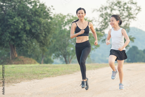two female runners jogging outdoors in forest in autumn nature..running sporty mother and daughter. woman and child jogging in a park. outdoor sports and fitness family.