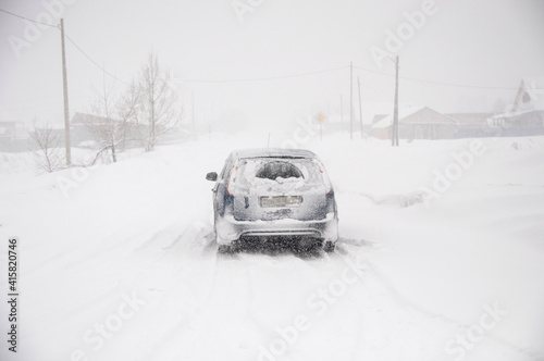 snowfall, a car on the road covered with snow