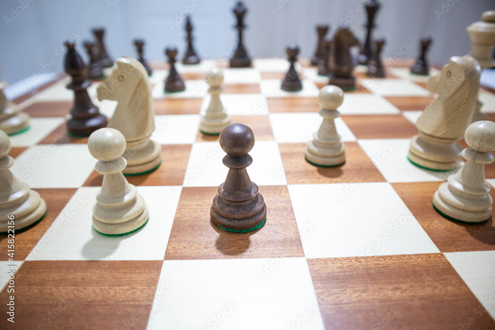 Playing wooden chess on a chessboard. Tactics and strategy. Black and white shapes. Playing wooden chess on a chessboard. Tactics and strategy. Black and white shapes.
