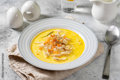 Chicken breast in a creamy broth. Chicken with vegetables and cream. Chicken soup in a bowl on the light gray kitchen table