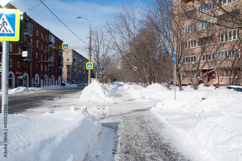 Fototapeta premium Winter city landscape. Large drifts along houses after a snowfall.