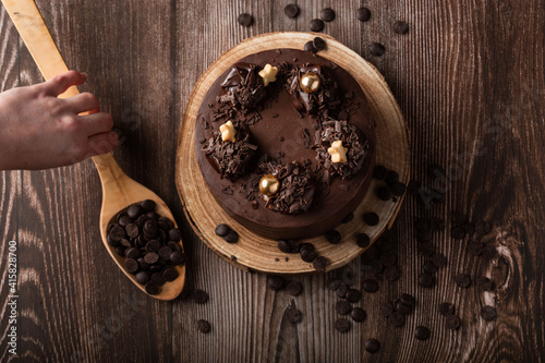 Overhead view of the chocolate cake, with chocolate chips, a hand on the spoon