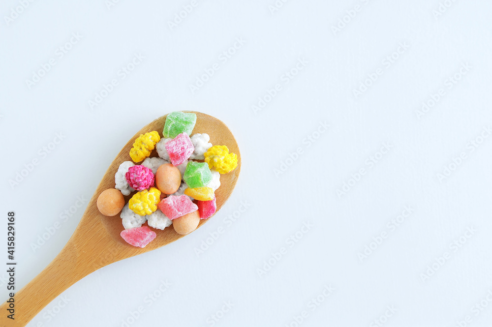 Multicolored sweets and dry fruit slices on wooden spoon. White background. Multicolored sweets and dry fruit slices on wooden spoon. White background.