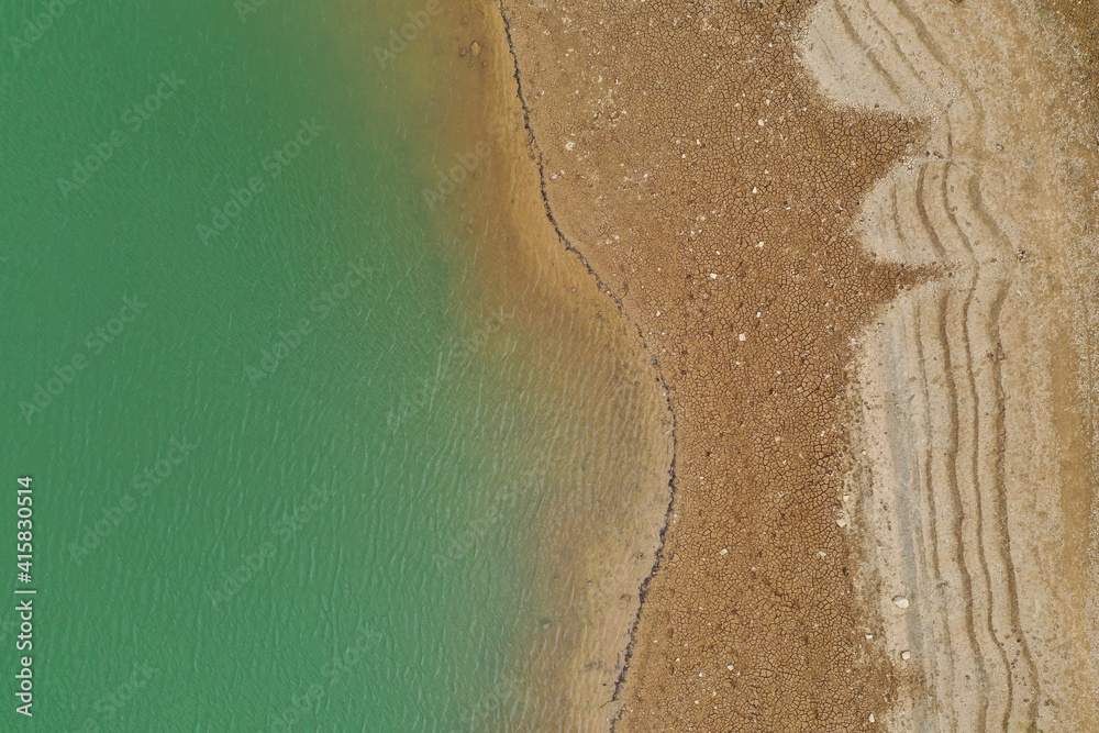 Aerial top view pattern of clear river water and sand on the river bank