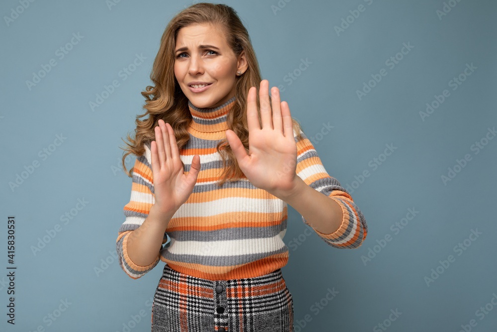 Portrait of young pretty beautiful sad angry dissatisfied blonde woman with sincere emotions wearing casual striped sweater isolated over blue background with copy space and showing no gesture and Portrait of young pretty beautiful sad angry dissatisfied blonde woman with sincere emotions wearing casual striped sweater isolated over blue background with copy space and showing no gesture and
