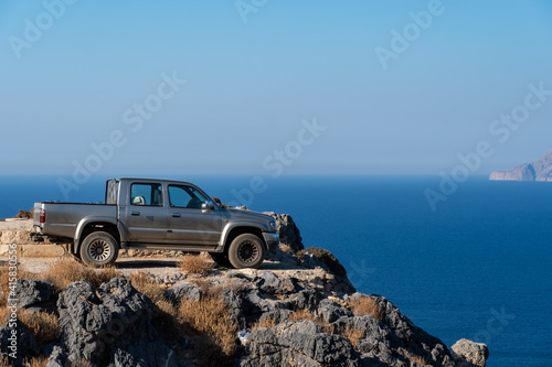 Road vehicle on the edge of a steep cliff. 4x4 car during extreme mountain safari in Crete, Balos road. Grece