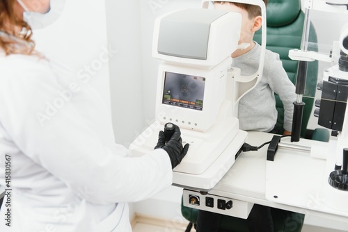 Modern medical equipment. Close up of ophthalmologist using auto refractometer while examining child eyes