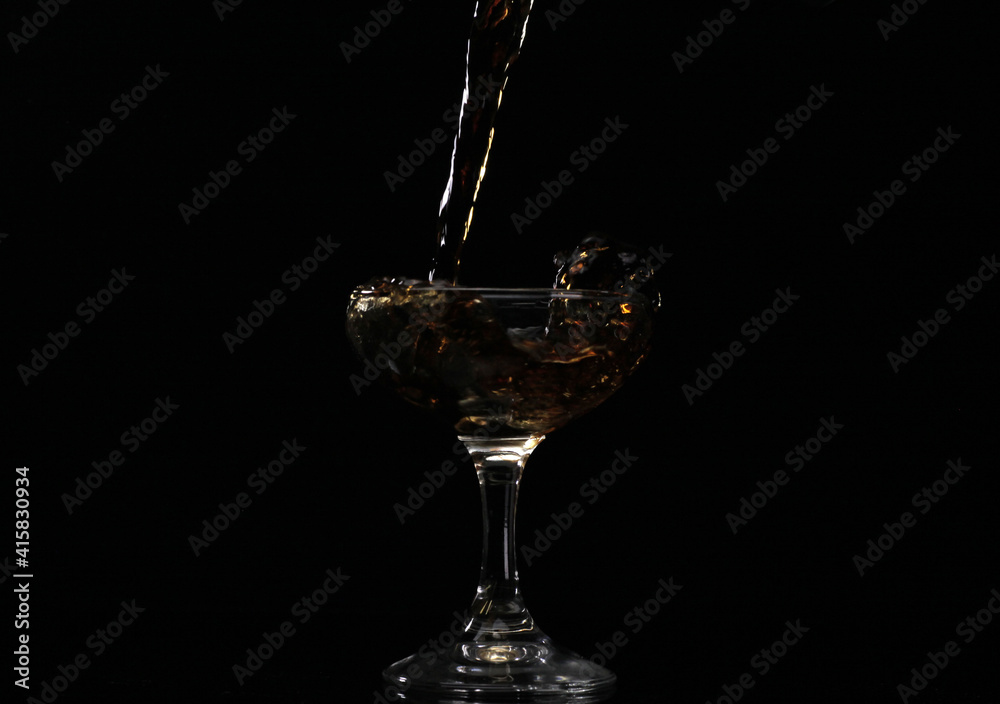Pouring drink into the glass with black background Pouring drink into the glass with black background