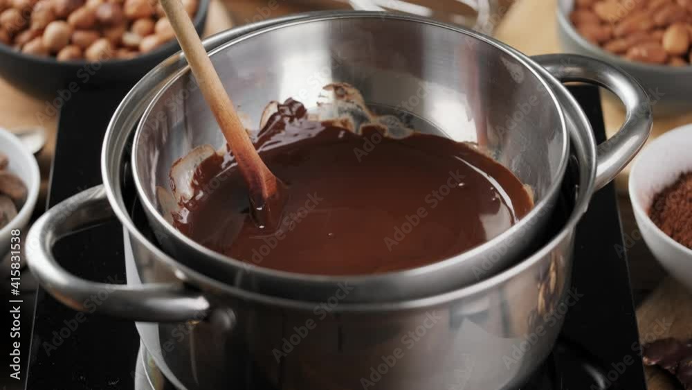 Dark chocolate is melted in a bowl on a steam bath. Liquid chocolate, confectionery. Making chocolate at home. Dark chocolate is melted in a bowl on a steam bath. Liquid chocolate, confectionery. Making chocolate at home.