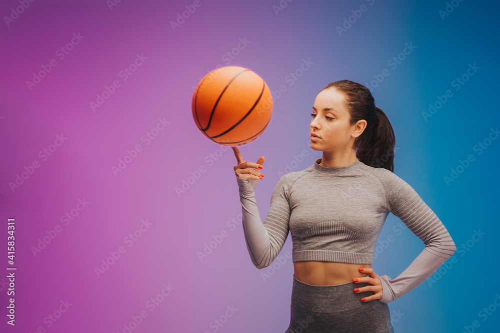 Fashion portrait of young fit and sportive caucasian woman with basketball on gradient background. Perfect body ready for summertime. Beauty, resort, sport concept