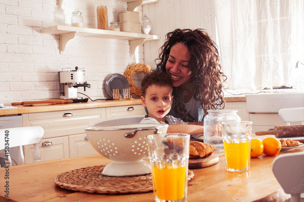 young pretty african american mother with little cute son on kitchen in morning preparing breakfast, lifestyle people concept