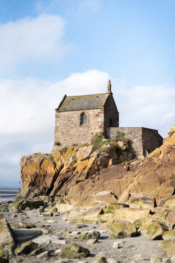 Vertical photo of a small chapel in front of the sea