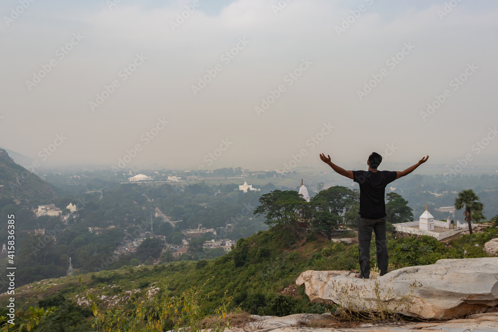 man in victory pose isolated at rock and watching amazing landscape