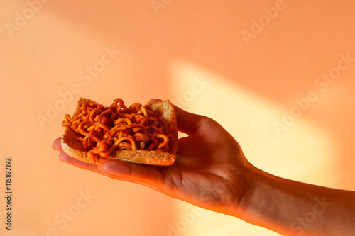 hand holding a slice of noodle pizza 