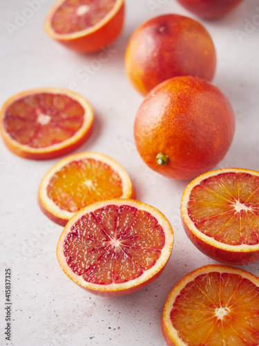 close up composition of whole and sliced blood oranges on a stone surface