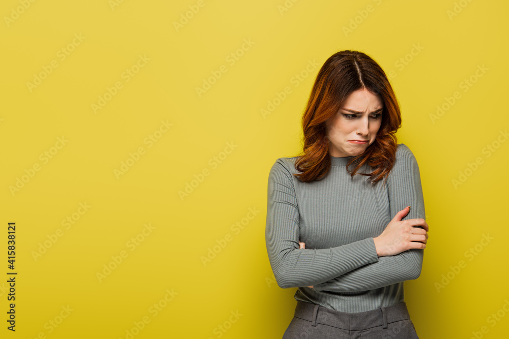 offended woman with curly hair standing with crossed arms on yellow offended woman with curly hair standing with crossed arms on yellow