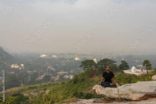man meditating isolated at rock with amazing landscape