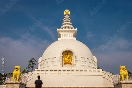 monk praying at buddhist stupa isolated with amazing blue sky from unique perspective