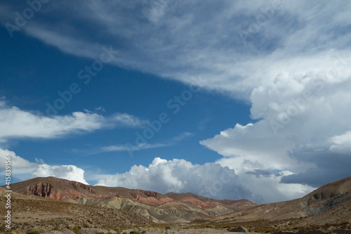 Arid landscape. View of the desert sand, dunes, and colorful hills under a beautiful sky with clouds.