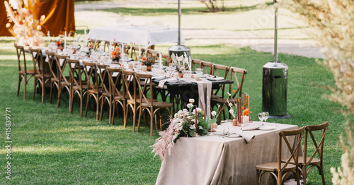 Chairs and table for newlyweds decorated with candles, served with cutlery, crockery and covered with tablecloth