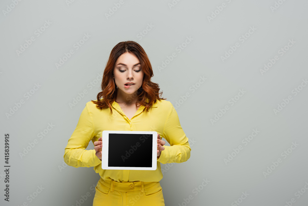 curious woman holding digital tablet with blank screen on grey curious woman holding digital tablet with blank screen on grey