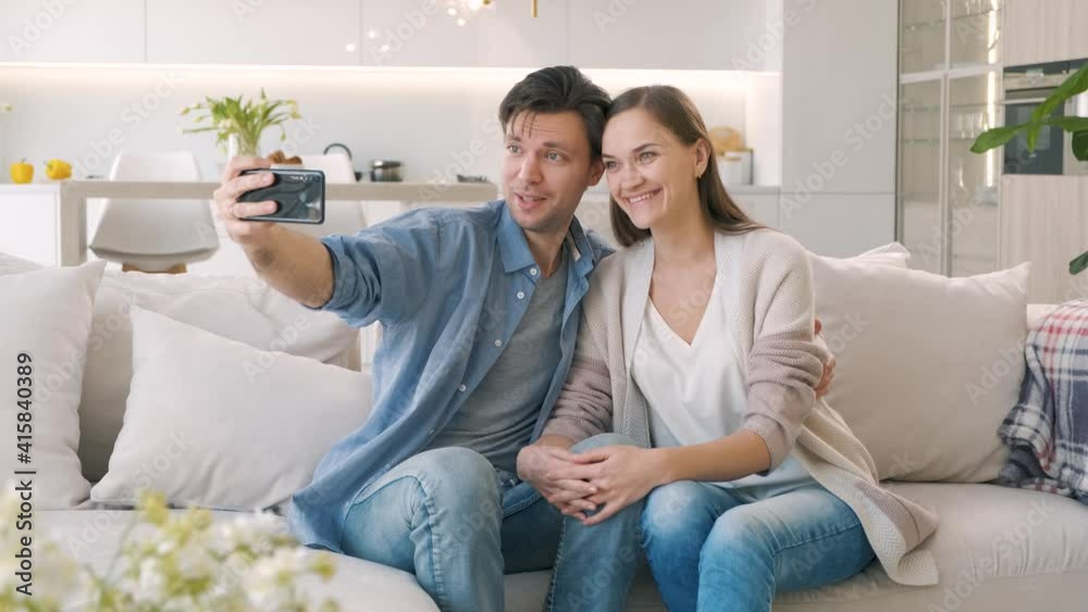 Cheerful couple takes selfie while sitting on the couch at home Cheerful couple takes selfie while sitting on the couch at home