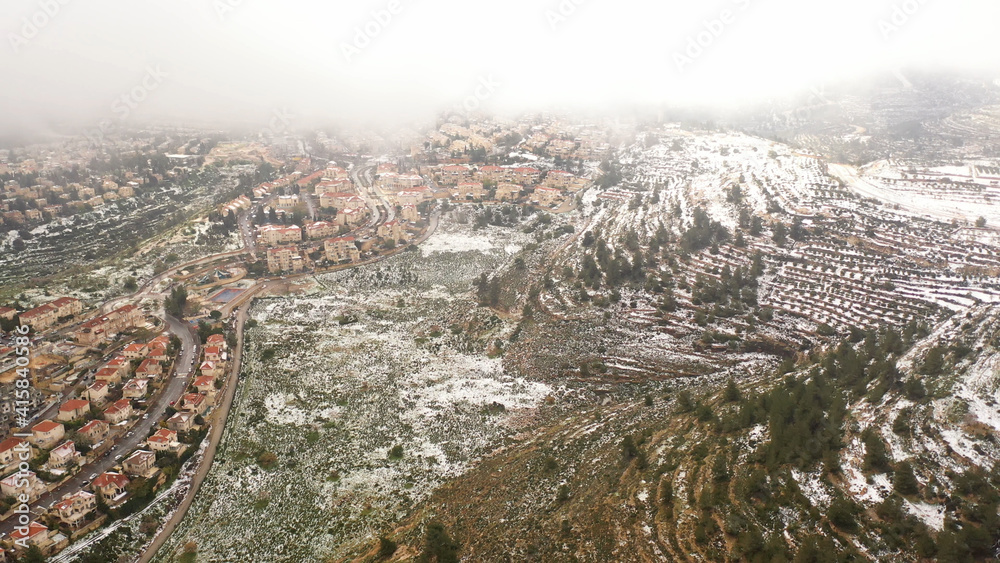 Jerusalem red rooftops in the snow aerial view
,drone view over mevasert zion close to Jerusalem covered with snow, February 2021
