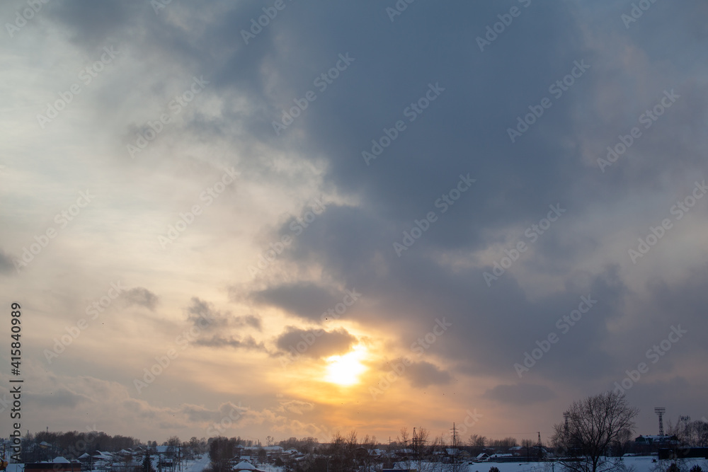 The sun among the clouds over the winter city. Beautiful background