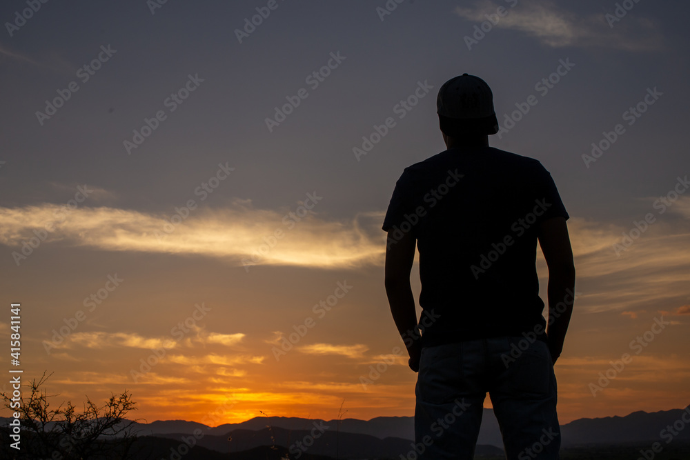 Hombre a contraluz en un atardecer naranja Hombre a contraluz en un atardecer naranja