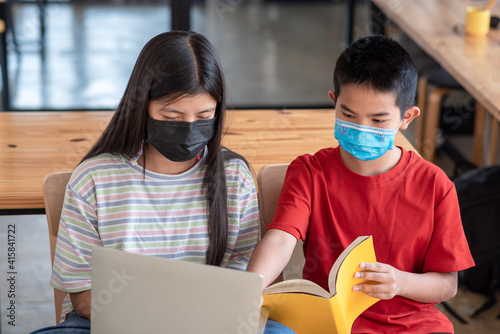Brothers and sisters Asian studies online together at home. Wear a mask Prevent germs.