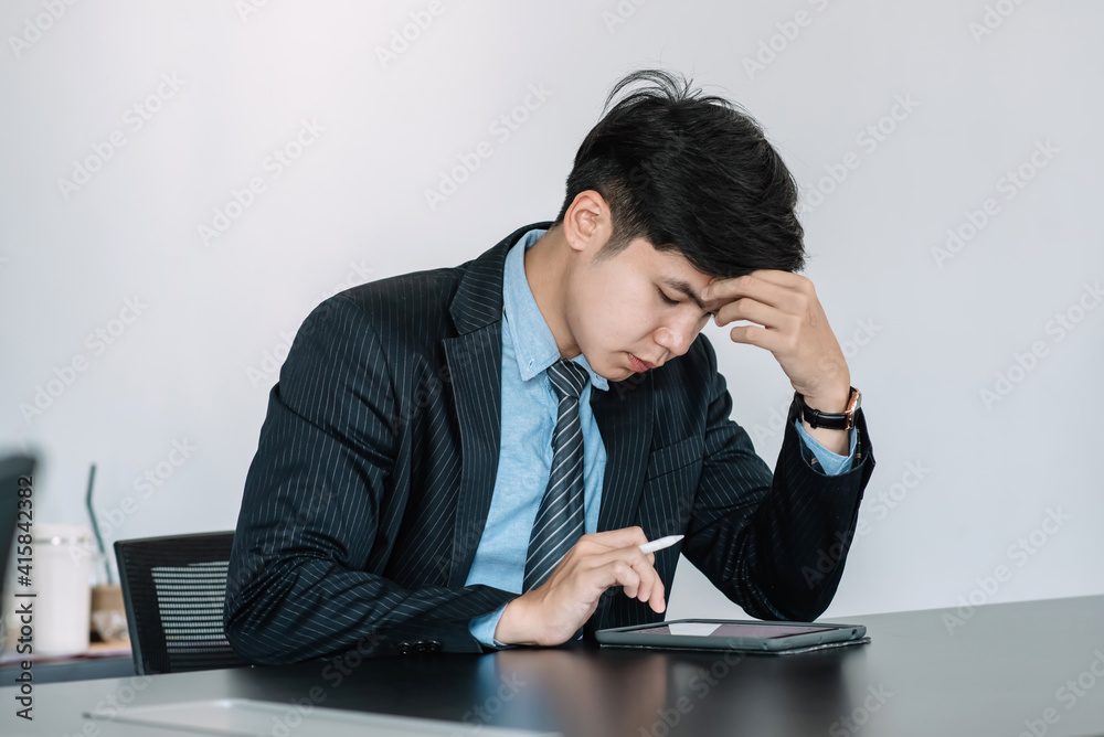 Asian businessman are tired and stressed about working on a tablet at the office. Asian businessman are tired and stressed about working on a tablet at the office.