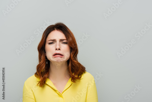 Fotografie discouraged woman looking at camera and grimacing isolated on grey