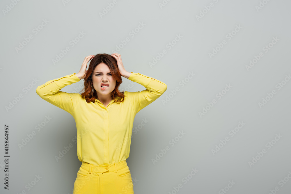 displeased woman biting lip and touching head on grey displeased woman biting lip and touching head on grey