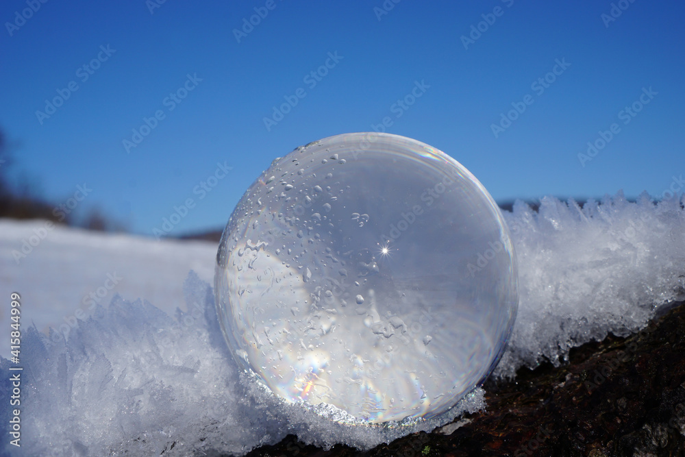 Eine Fotokugel liegt auf einem Baumstamm umgeben von Schnee Eine Fotokugel liegt auf einem Baumstamm umgeben von Schnee