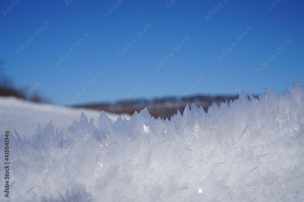 Schneekristalle in Nahaufnahme mit blauen Himmel im Hintergrund