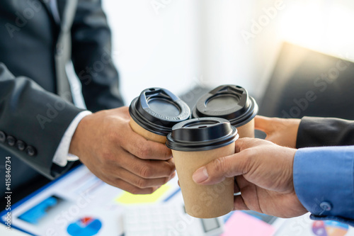 Asian entrepreneurship team clink hot coffee cups after the success of Project agreements that have been invested together between companies in the office.