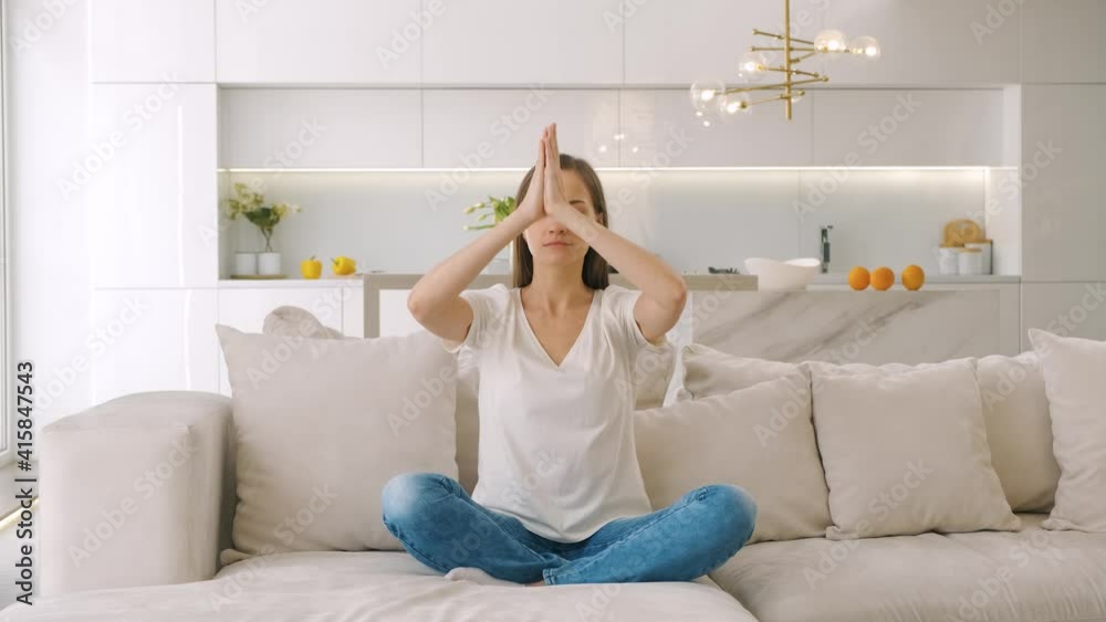 Young woman sitting on the sofa and doing meditation Young woman sitting on the sofa and doing meditation