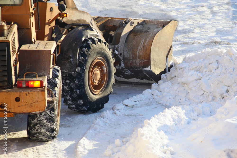 One heavy wheeled tractor removes a snow with scraper shovel blade