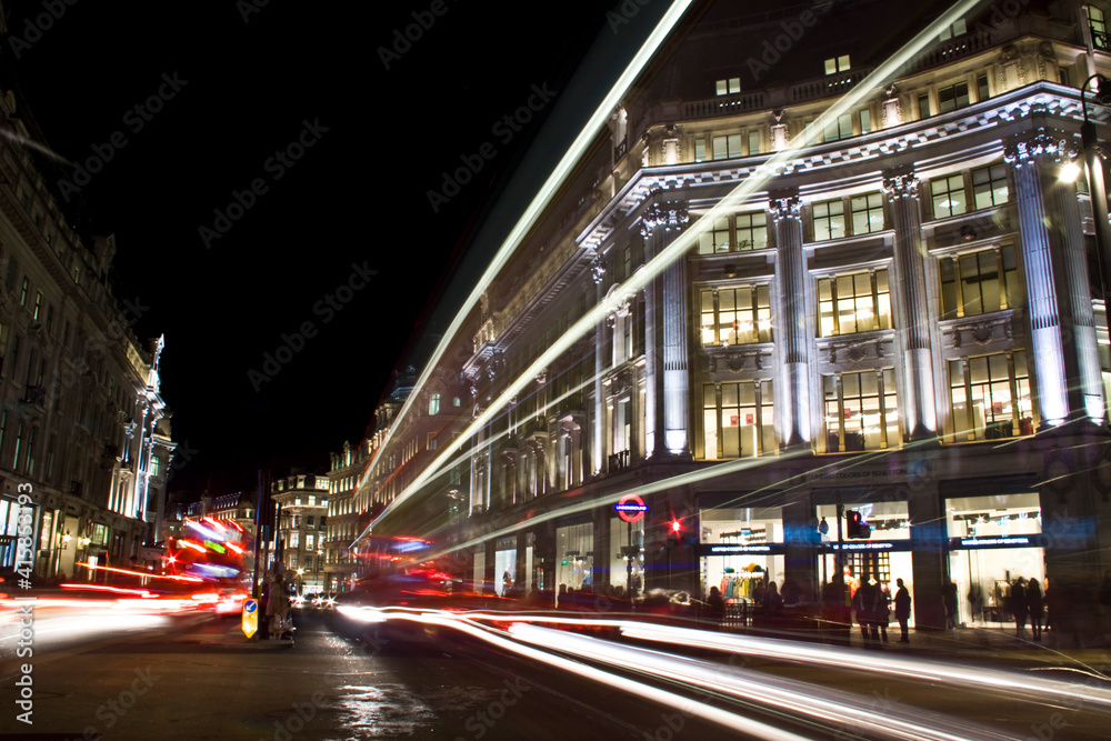 Night trails of vehicles moving across the shopping area in London 's Oxford Circus.