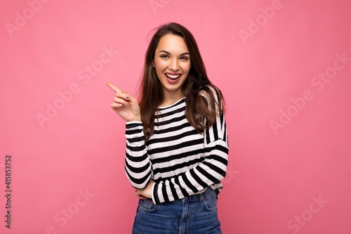 Portrait of beautiful fascinating emotional positive joyful happpy female promoter pointing to the side at copy space for advertising wearing hipster outfit isolated over background wall with empty © Ivan Traimak