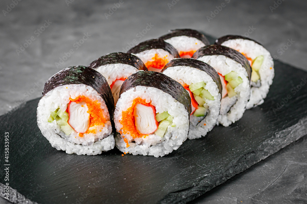 appetizing sushi roll futomaki with cucumber crab stick and masago on a black stone plate appetizing sushi roll futomaki with cucumber crab stick and masago on a black stone plate