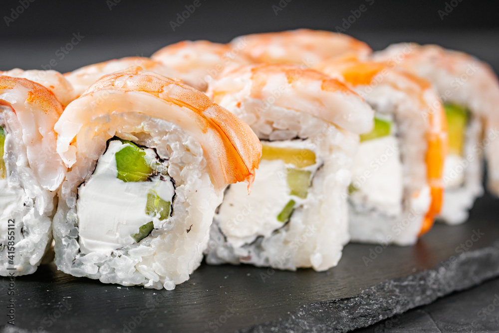 appetizing sushi roll philadelphia with avocado cheese cucumber and shrimp on a black stone plate appetizing sushi roll philadelphia with avocado cheese cucumber and shrimp on a black stone plate